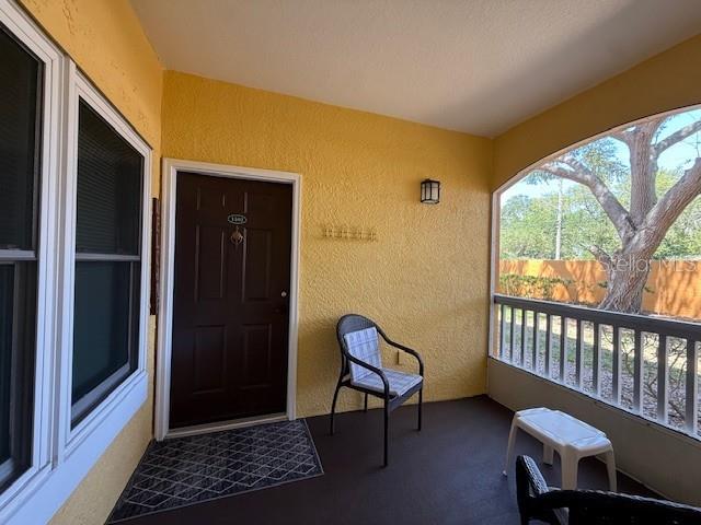 A covered porch features yellow walls, a dark brown door, and a single patio chair — 10764 70TH AVENUE UNIT 1102, SEMINOLE, FL