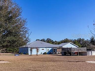 A light blue single-story house with a metal roof and a wooden deck — 1677 W HIGHWAY 316, CITRA, FL