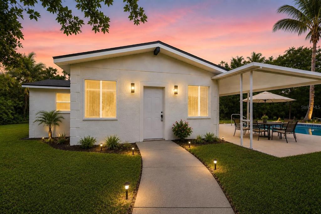 A kidney-shaped swimming pool with a rock water feature sits in a grassy backyard — 17503 GALVESTON STREET, SPRING HILL, FL