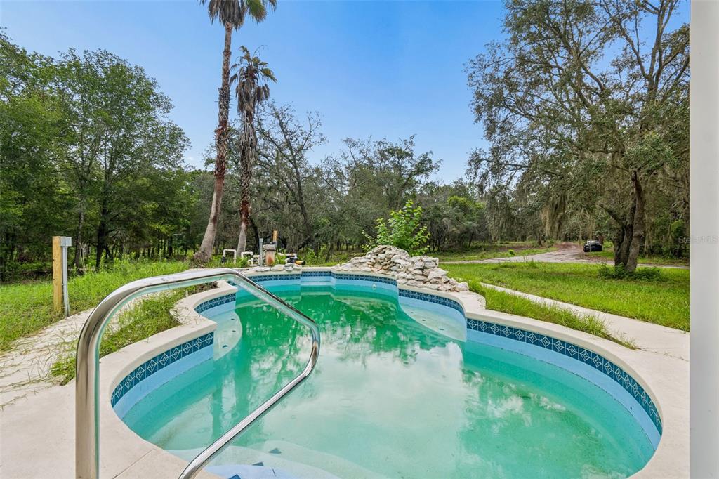A white single-story house with a concrete walkway, a small pool, and a covered patio — 17503 GALVESTON STREET, SPRING HILL, FL