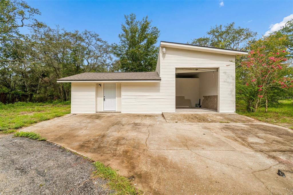 A detached garage with white siding, a brown shingled roof, and a concrete driveway — 17503 GALVESTON STREET, SPRING HILL, FL