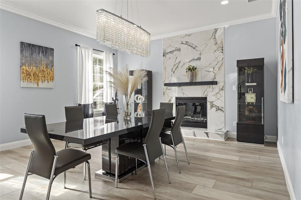 A dining room features a black table, modern chairs, a crystal chandelier, and a fireplace — 14485 SWITCH BACK ROAD, SPRING HILL, FL