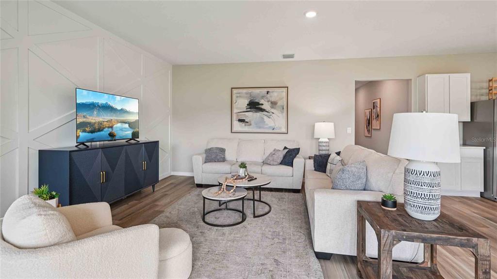 A living room features a white accent wall, a television console, and two beige sofas — 17066 NW 179TH WAY, ALACHUA, FL