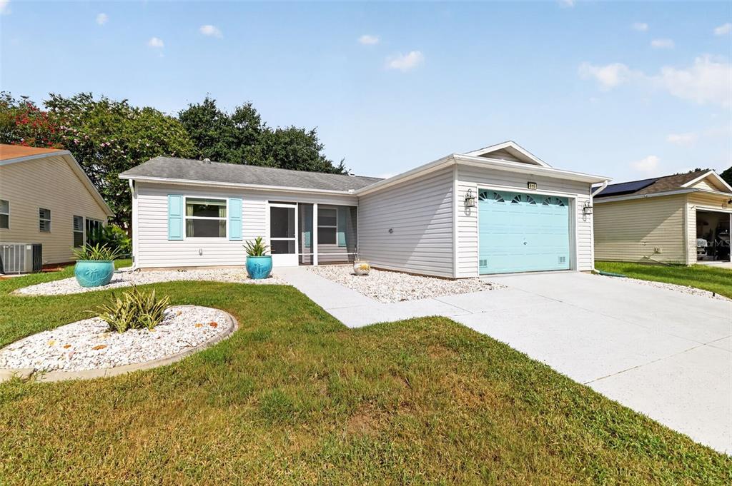 A single-story house with light gray siding, a light blue garage door, and a front lawn — 815 GRAND VISTA TRAIL, LEESBURG, FL