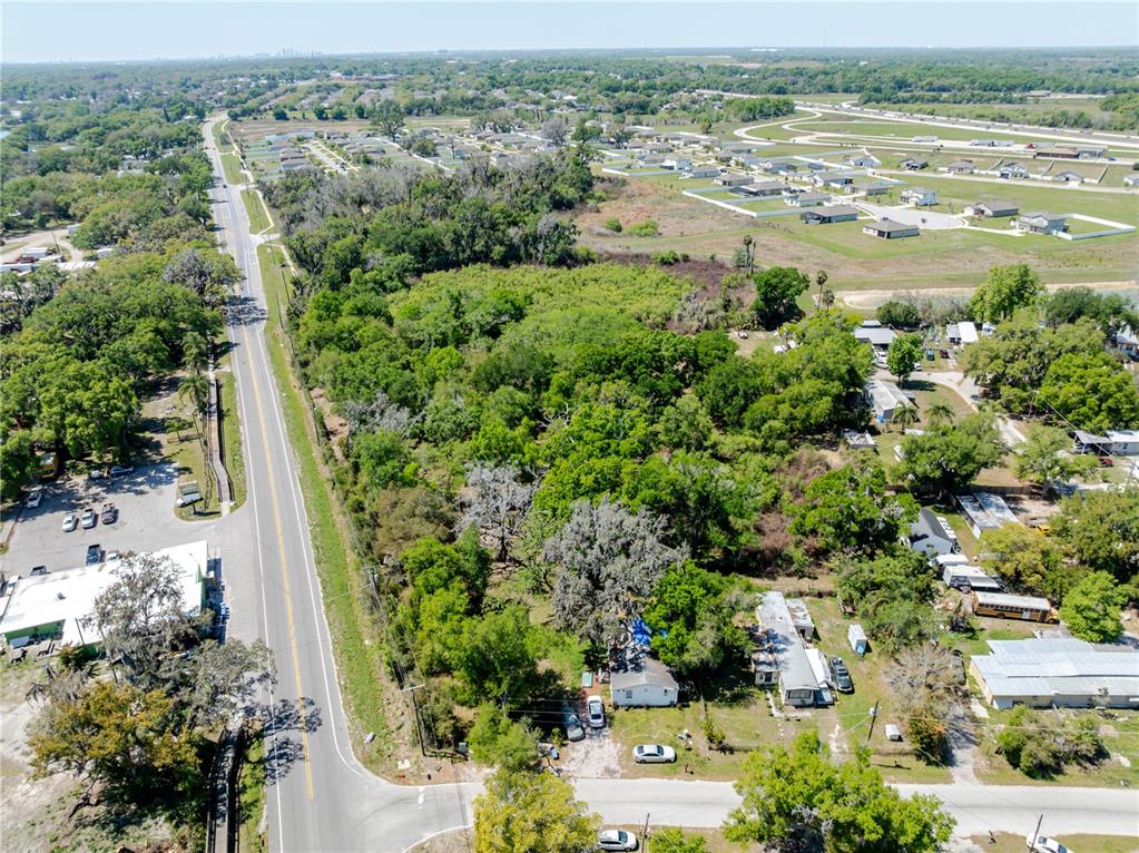 An aerial view shows a wooded lot bordered by a road and residential properties — 1120 NORTHWOOD DRIVE, SEFFNER, FL