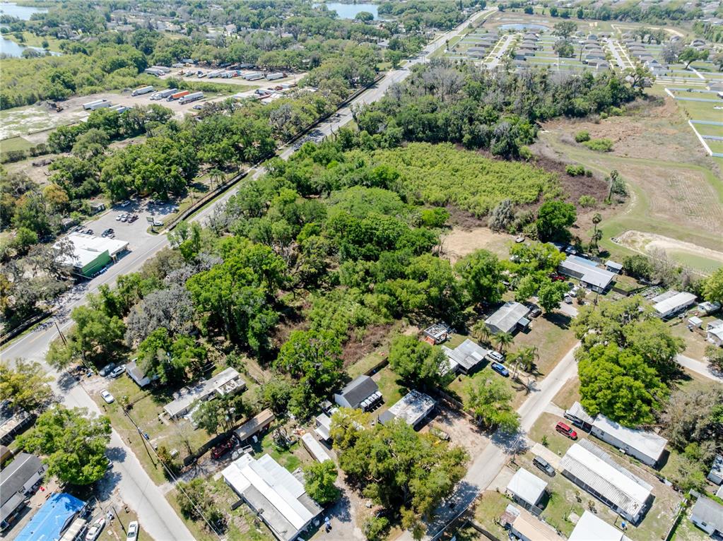 An aerial view shows a residential area with scattered houses, dense trees, and nearby roads — 1120 NORTHWOOD DRIVE, SEFFNER, FL