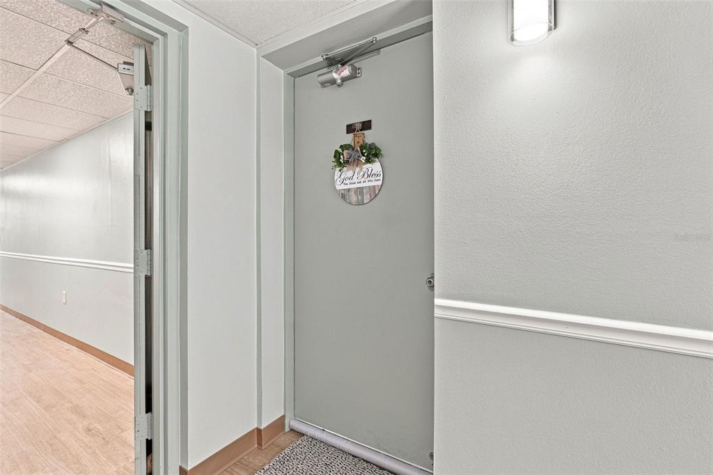 A gray door with a decorative sign hangs in a hallway with light-colored walls — 21260 BRINSON AVENUE UNIT 110, PORT CHARLOTTE, FL