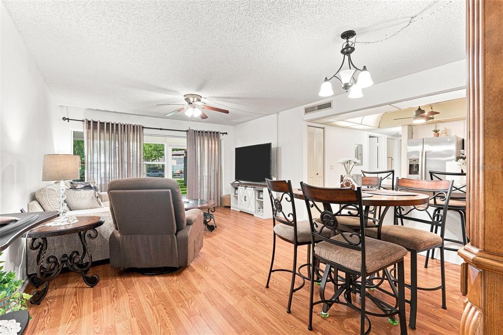 A living and dining area features wood-look flooring, a ceiling fan, and a chandelier — 21260 BRINSON AVENUE UNIT 110, PORT CHARLOTTE, FL
