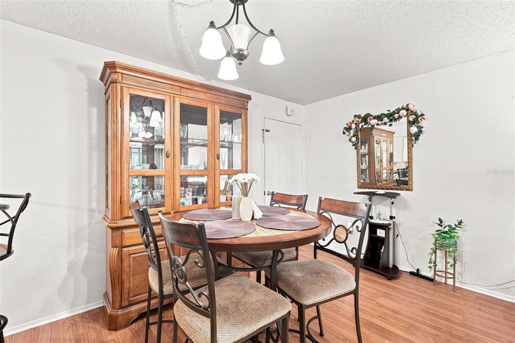 A dining room features a wooden hutch, a round table with four chairs, and a mirror — 21260 BRINSON AVENUE UNIT 110, PORT CHARLOTTE, FL