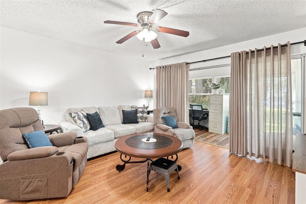 A living room features a light-colored sofa, two recliners, a round coffee table, and curtains — 21260 BRINSON AVENUE UNIT 110, PORT CHARLOTTE, FL