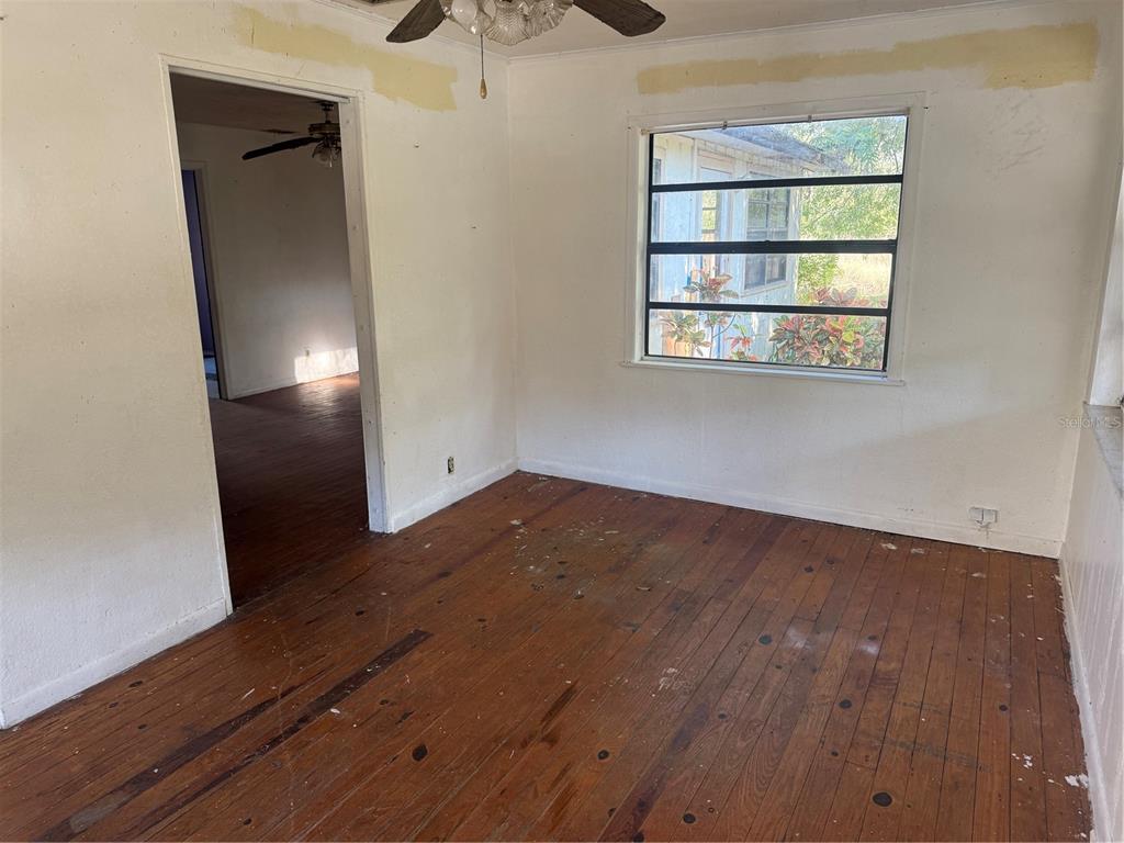 An empty room with hardwood floors, white walls, and a window looking outside — 830 BLOXHAM AVENUE, PUNTA GORDA, FL