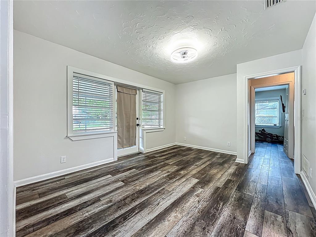 An empty room with wood-look flooring, a textured ceiling, and a doorway leading to another room — 2542 S PALMETTO AVENUE, SANFORD, FL