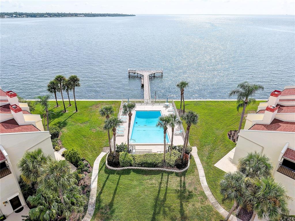 An aerial view shows a swimming pool situated between two buildings overlooking a large body of water — 7510 SUNSHINE SKYWAY LANE S UNIT T13, ST PETERSBURG, FL