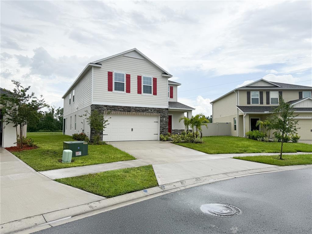 A two-story suburban house with light siding, red shutters, and a stone-accented garage — 4152 SAGEFIELD DR, HARMONY, FL