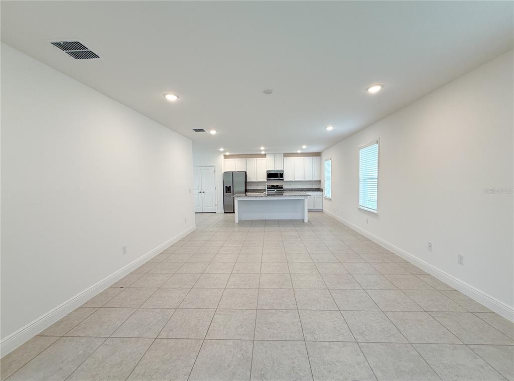 An open-concept kitchen and living area features white cabinetry, a central island, and tile flooring — 4152 SAGEFIELD DR, HARMONY, FL