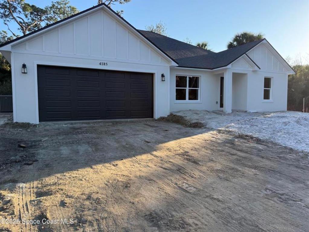A white single-story house with a dark garage door and unfinished dirt front yard — 3643 ONEIDA STREET, COCOA, FL