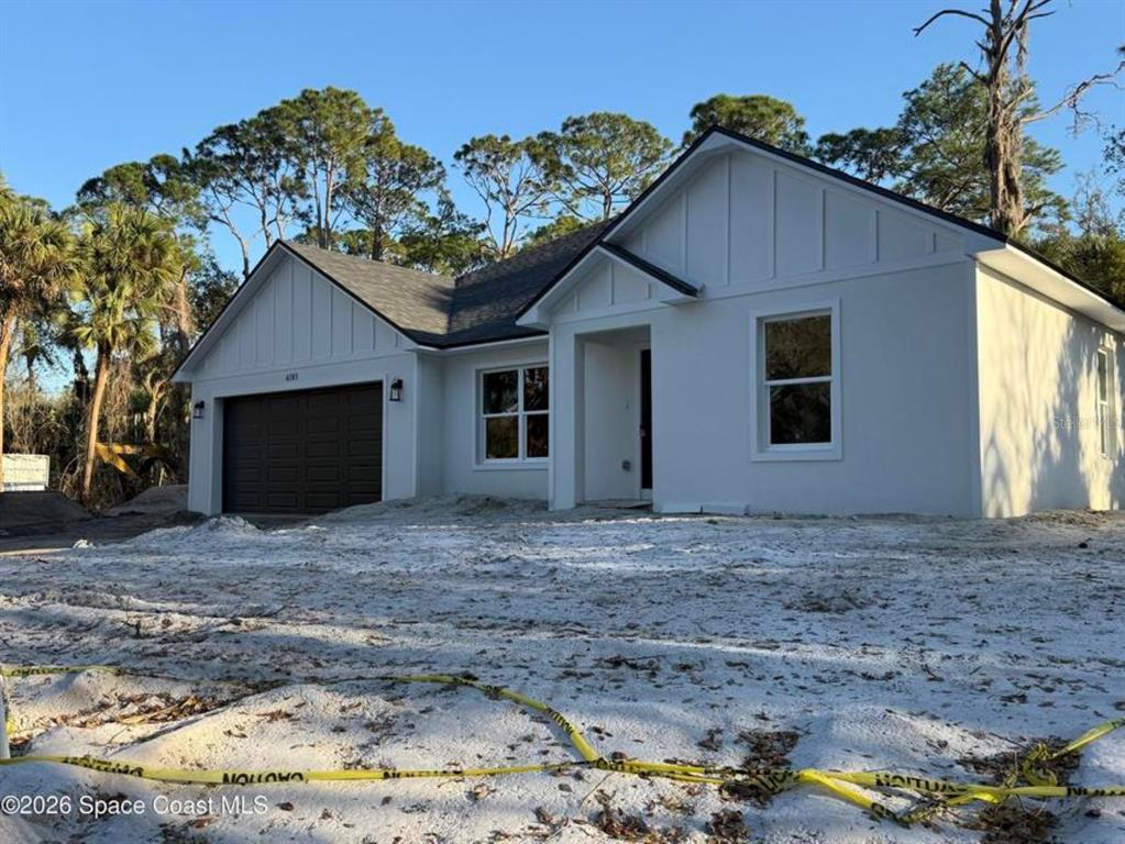 A newly constructed single-story house with a white exterior, dark garage door, and sandy yard — 3643 ONEIDA STREET, COCOA, FL