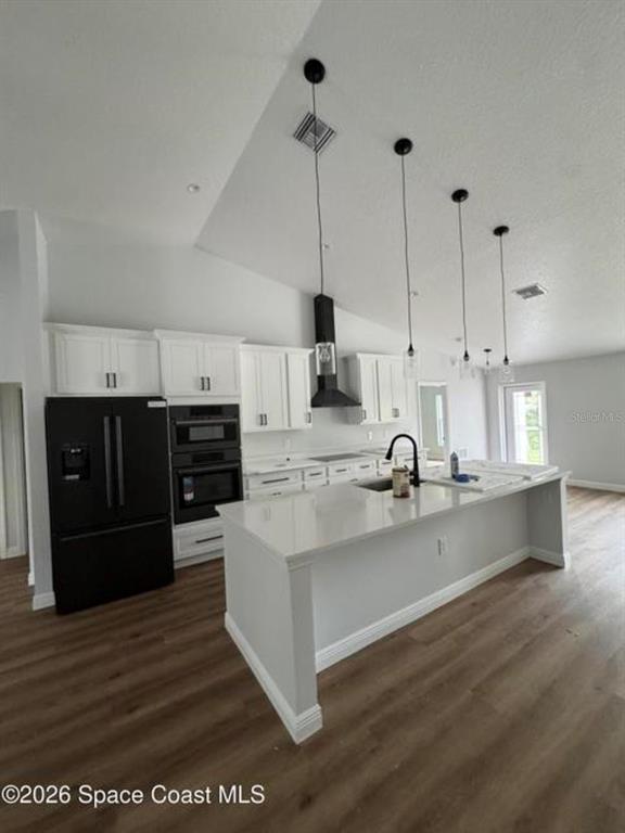 A modern kitchen features white cabinets, a black refrigerator, and a large central island — 3643 ONEIDA STREET, COCOA, FL