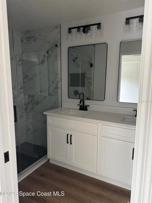 A bathroom features a double vanity with white cabinets, black hardware, and a glass-enclosed shower — 3643 ONEIDA STREET, COCOA, FL