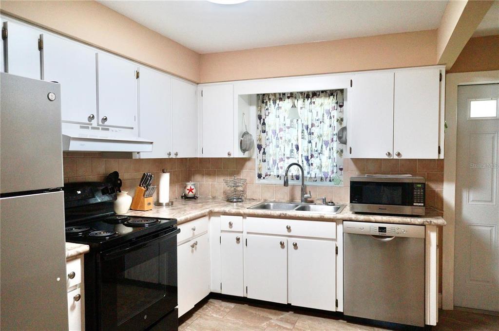 An empty bedroom features light blue walls, grey wood-look flooring, and windows with blinds — 6890 VERSAILLES N UNIT 10, PINELLAS PARK, FL