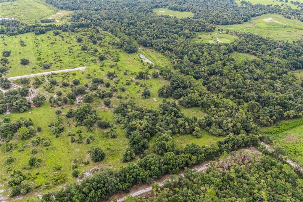 An aerial view shows a large, grassy pasture dotted with trees and patches of dense forest — 37720 KVILLE ROAD, MYAKKA CITY, FL