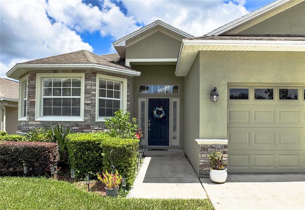 The exterior of a single-story house features a stone-accented facade, a blue front door, and garage — 6335 SILVER LEAF LANE, LAKELAND, FL