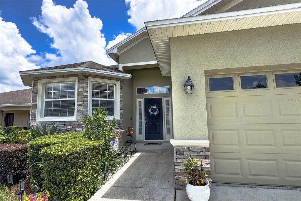 The exterior of a house features a stone-accented bay window, a dark blue door, and a garage — 6335 SILVER LEAF LANE, LAKELAND, FL
