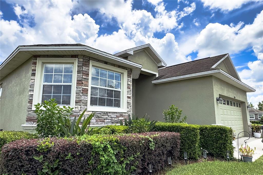 A single-story house with a stone-accented bay window, stucco siding, and a two-car garage — 6335 SILVER LEAF LANE, LAKELAND, FL