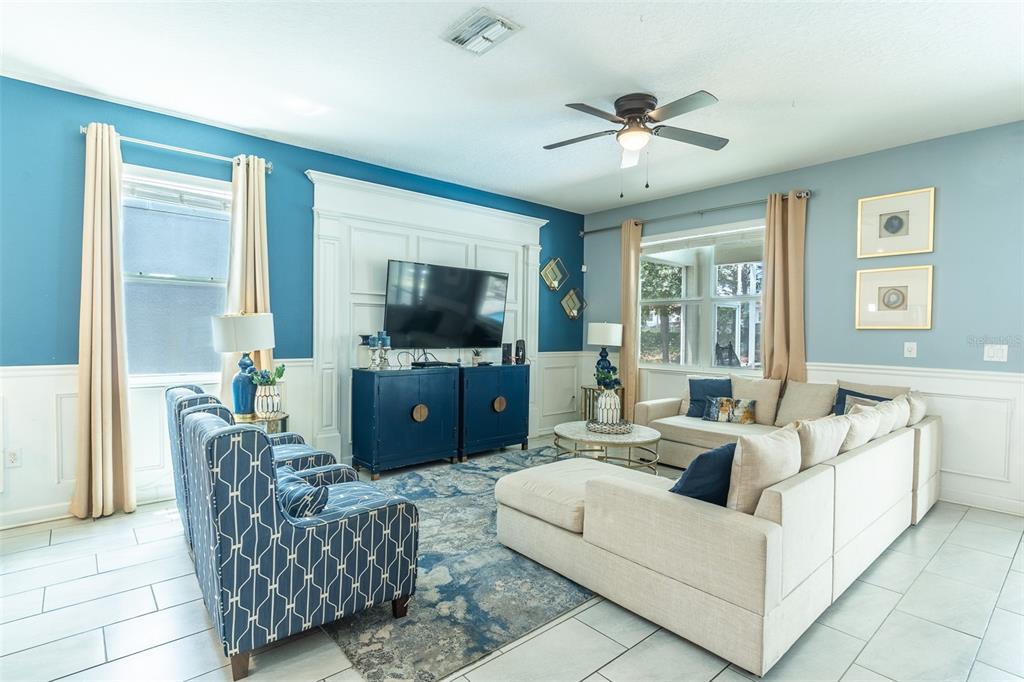 A living room features blue walls, white wainscoting, a sectional sofa, and a patterned armchair — 1532 MAIDSTONE COURT, DAVENPORT, FL