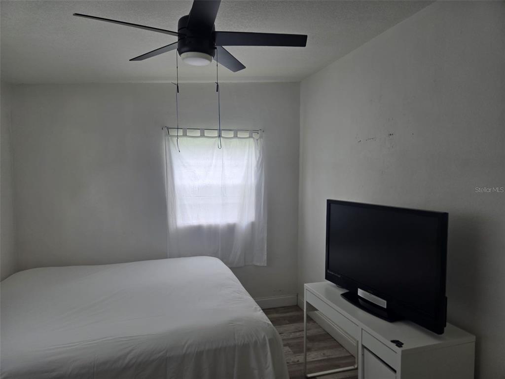 A bedroom features light wood-look flooring, a wooden dresser, a bed, and a ceiling fan — 4810 DEAUVILLE DRIVE, ORLANDO, FL