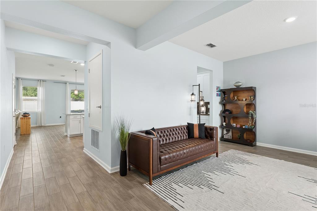 A living area features a brown leather sofa, a dark wooden bookshelf, and tile flooring — 1855 BLACK MAPLE PLACE, OCOEE, FL