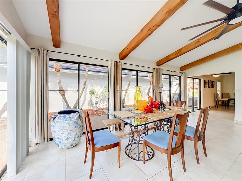 A dining room features a glass-topped table, wooden ceiling beams, and large sliding glass doors — 6328 GREENGATE DRIVE, ORLANDO, FL