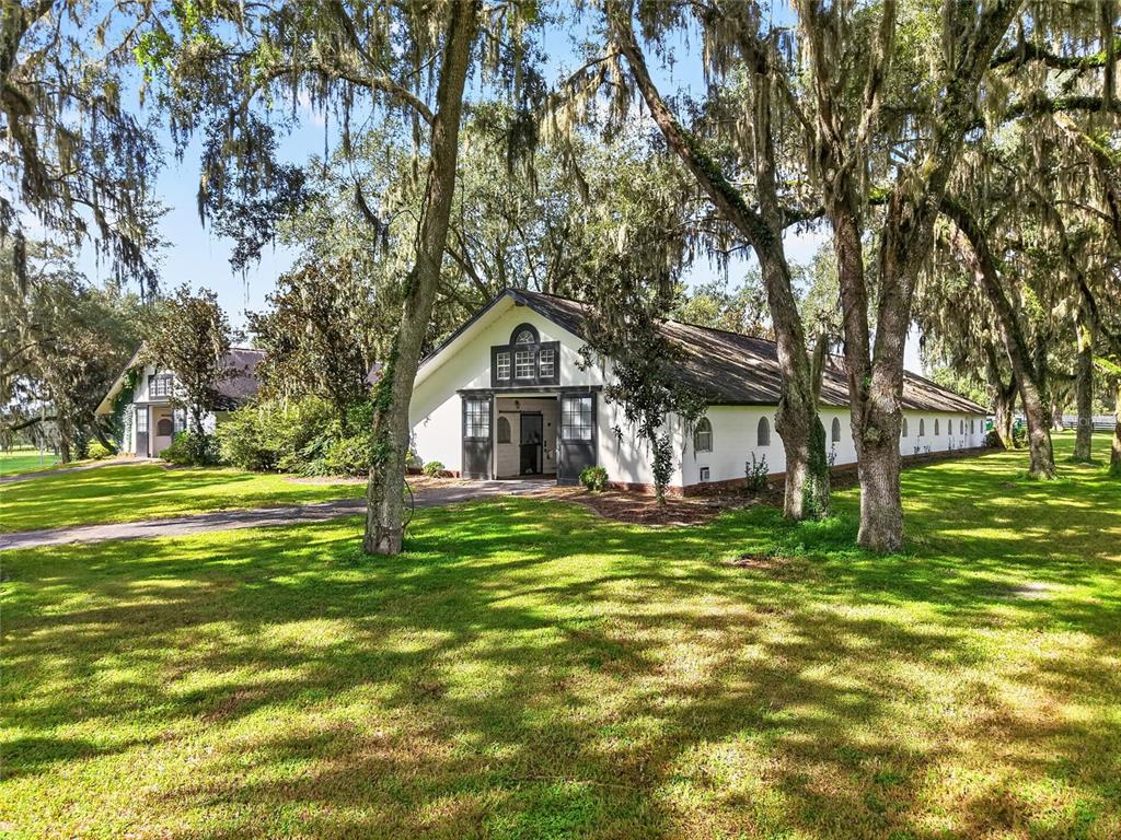A brick and white exterior wall features arched windows and two wicker chairs at night — 5540 SE 157TH STREET ROAD, SUMMERFIELD, FL