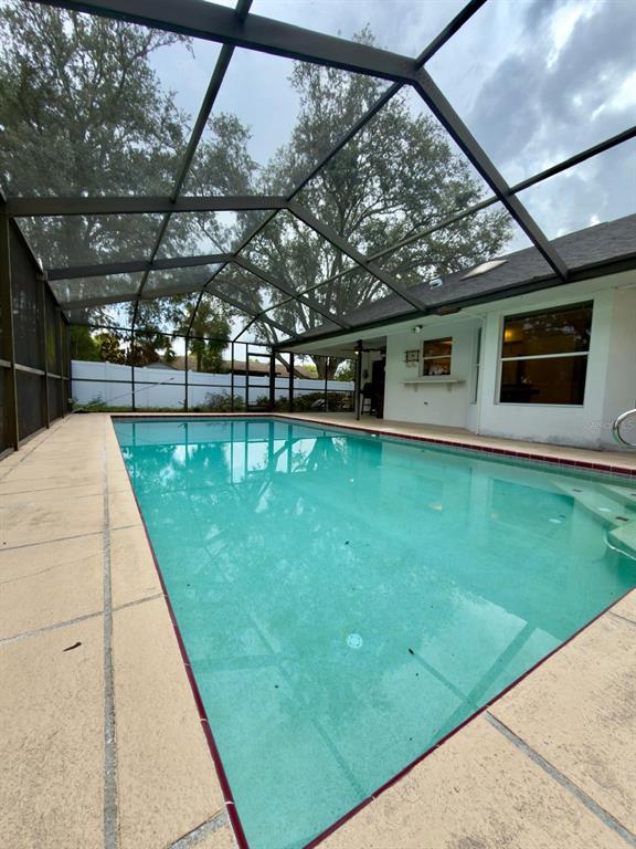 A rectangular swimming pool is enclosed by a screened lanai with a concrete patio deck — 13322 JAY COURT, SPRING HILL, FL
