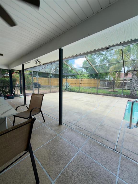 A covered patio with a pool enclosure, tiled flooring, and a view of the backyard — 13322 JAY COURT, SPRING HILL, FL