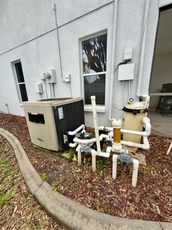 An exterior view of a pool heater and filtration system installed against a house wall — 13322 JAY COURT, SPRING HILL, FL
