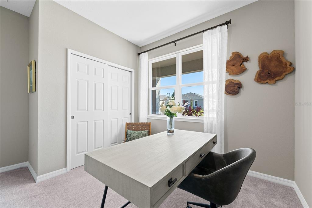 A home office features a light wood desk, a dark chair, and wall-mounted wood decor — 23615 GRINDSTONE WAY, SORRENTO, FL