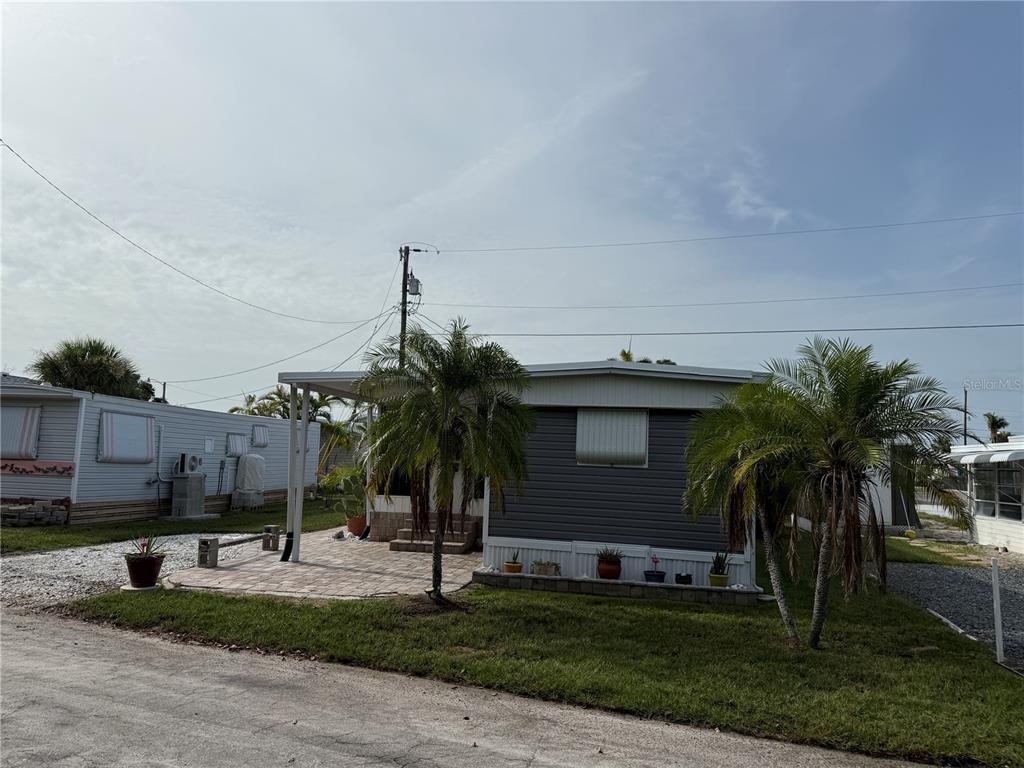 A manufactured home with a paved patio and two palm trees in the front yard — 2601 GULF DRIVE N UNIT S2, BRADENTON BEACH, FL