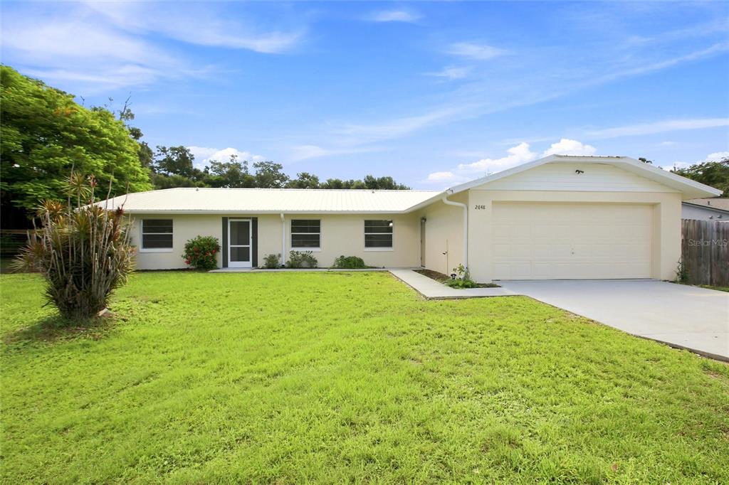 A single-story house with a white metal roof, light-colored siding, and an attached two-car garage — 2848 SE NORMAN AVENUE, ARCADIA, FL