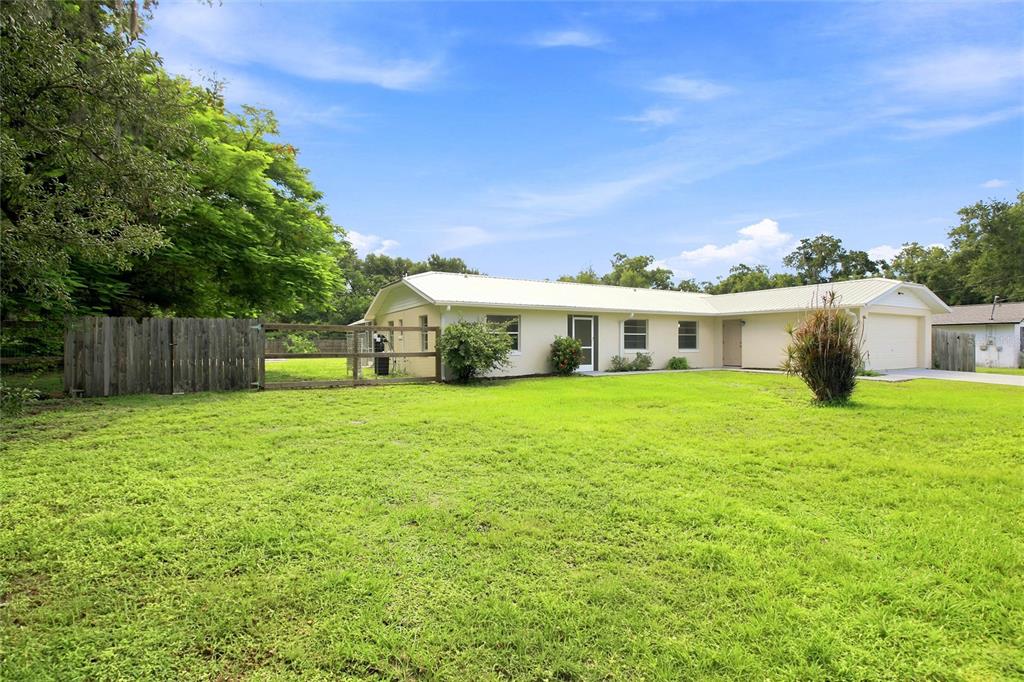 A single-story house with a metal roof, attached garage, and a large grassy front yard — 2848 SE NORMAN AVENUE, ARCADIA, FL
