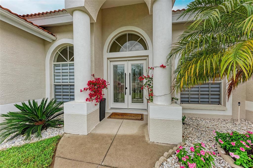 A single-story house with a white garage, tiled roof, and palm trees in the front yard — 7327 38TH COURT EAST, SARASOTA, FL