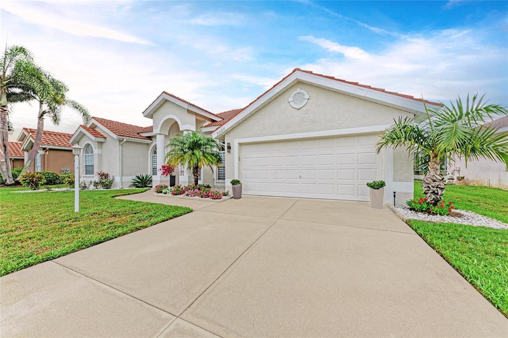 A single-story stucco house with a tiled roof, arched windows, and a front lawn — 7327 38TH COURT EAST, SARASOTA, FL