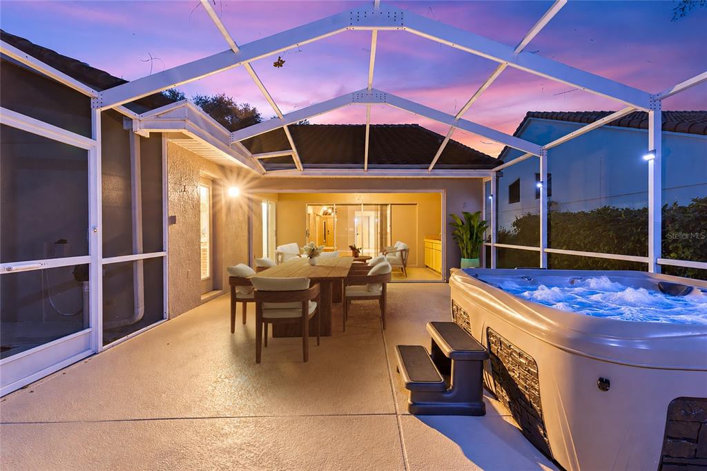 A screened-in patio features a dining set, a hot tub, and sliding glass doors — 9387 FRENCH QUARTERS CIRCLE, WEEKI WACHEE, FL
