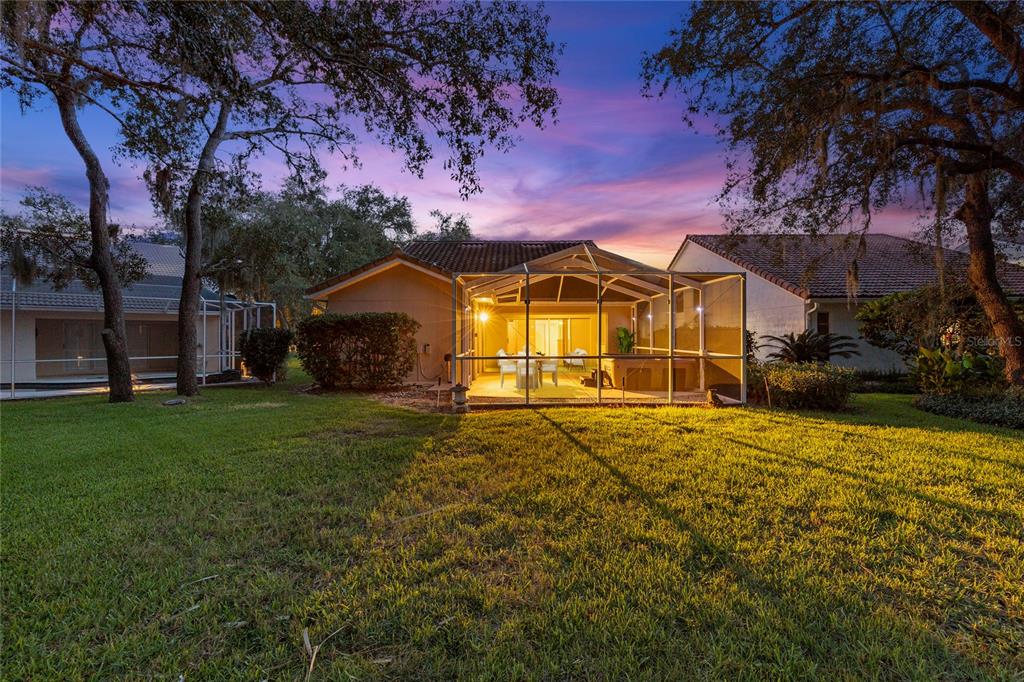 A rear view of a house with a screened-in patio at sunset — 9387 FRENCH QUARTERS CIRCLE, WEEKI WACHEE, FL