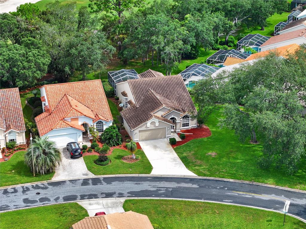 An aerial view shows two suburban houses with tiled roofs, driveways, and screened-in backyard pools — 9387 FRENCH QUARTERS CIRCLE, WEEKI WACHEE, FL
