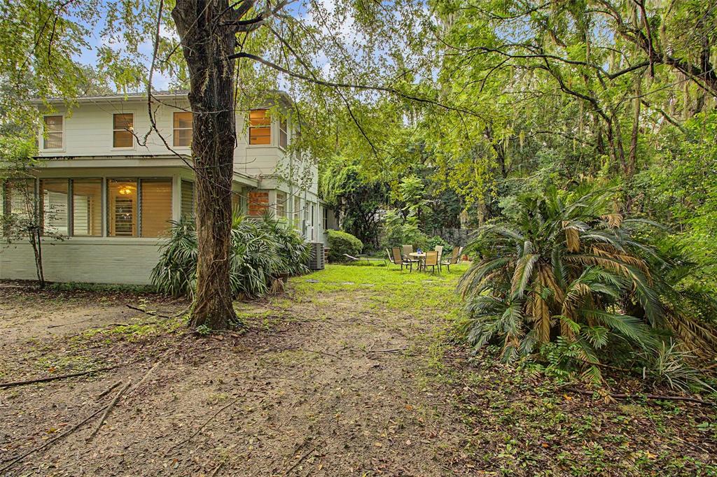 A kitchen features white cabinets, a stainless steel refrigerator, a black stove, and tile flooring — 2721 SW 3RD PLACE, GAINESVILLE, FL