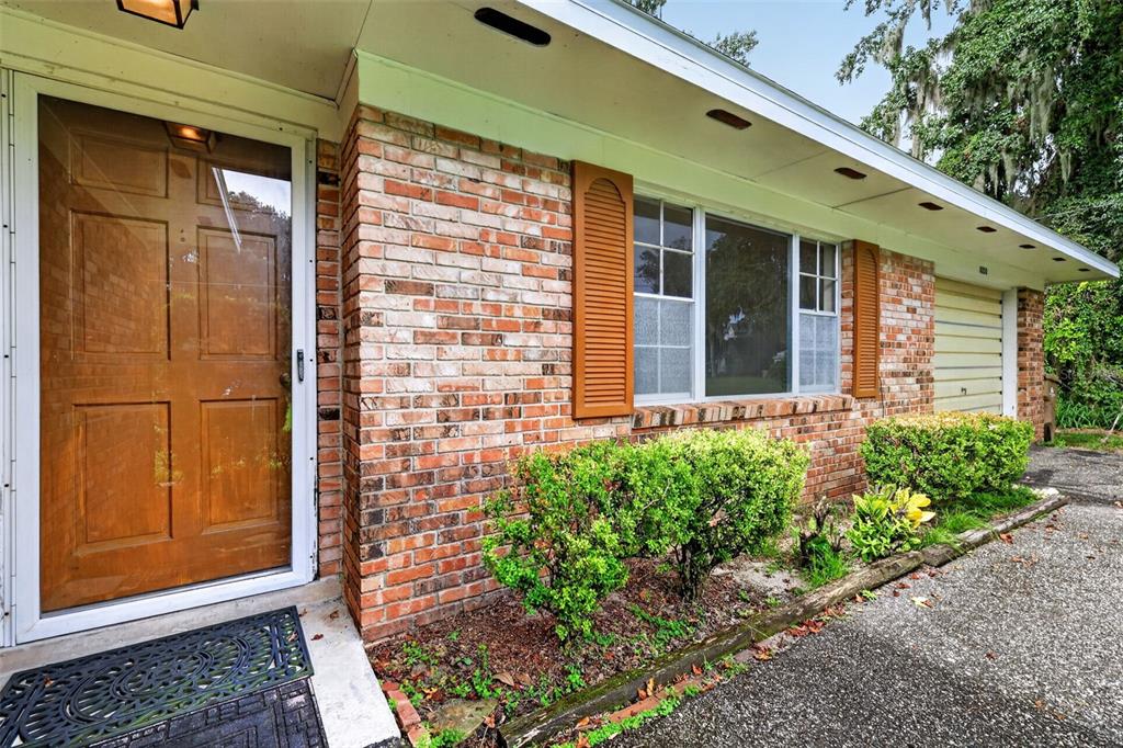 A brick exterior house features a wooden front door, a large window, and a garage — 8050 SPRING DRIVE, YALAHA, FL
