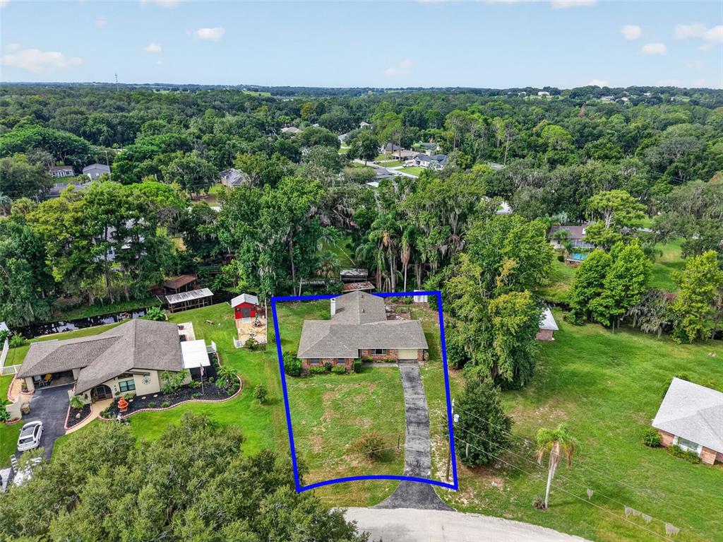 An aerial view shows a single-story brick house with a driveway and a large yard — 8050 SPRING DRIVE, YALAHA, FL