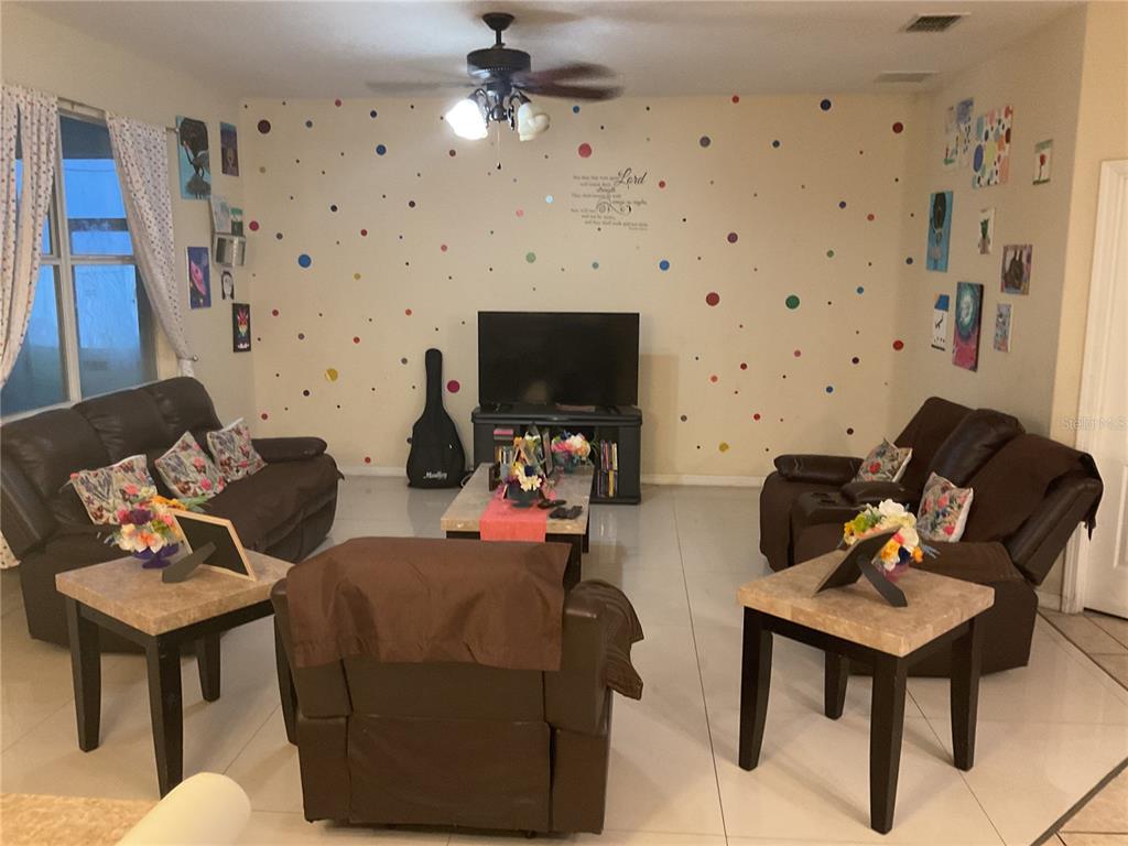 A living room features brown leather furniture, a polka-dot wall, and tile flooring — 11007 STANDING STONE DRIVE, WIMAUMA, FL