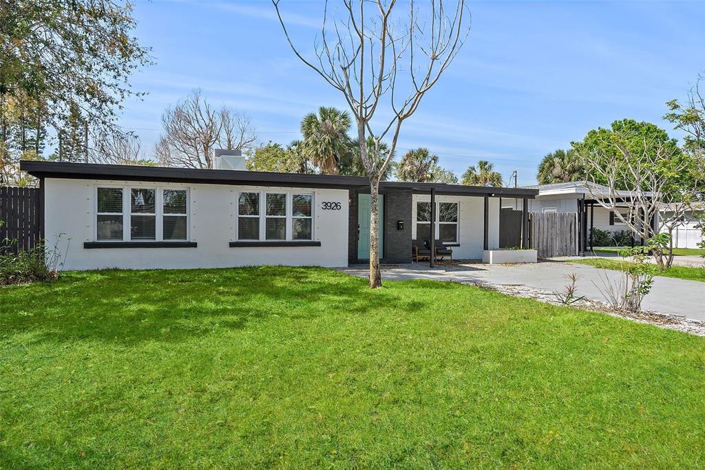 A single-story white house with a flat roof and a front lawn under a blue sky — 3926 HELENA STREET NE, ST PETERSBURG, FL
